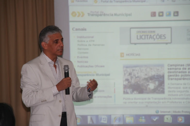 a man speaking into a microphone in front of a screen