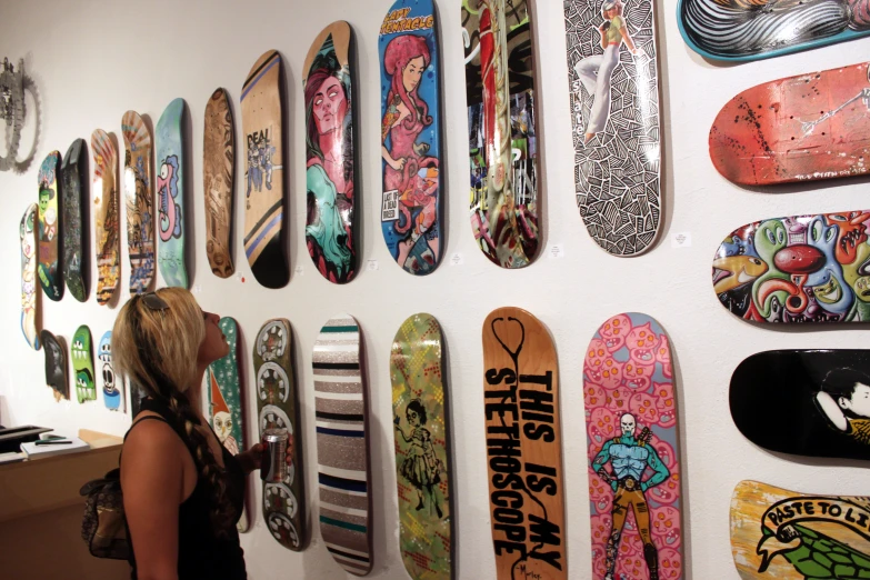 a person is looking at the different skate boards on the wall