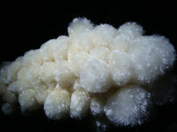 a pile of fluffy white cotton sits on a black surface