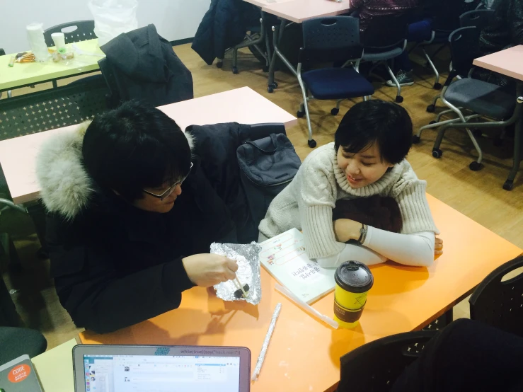 two people in an classroom with a laptop