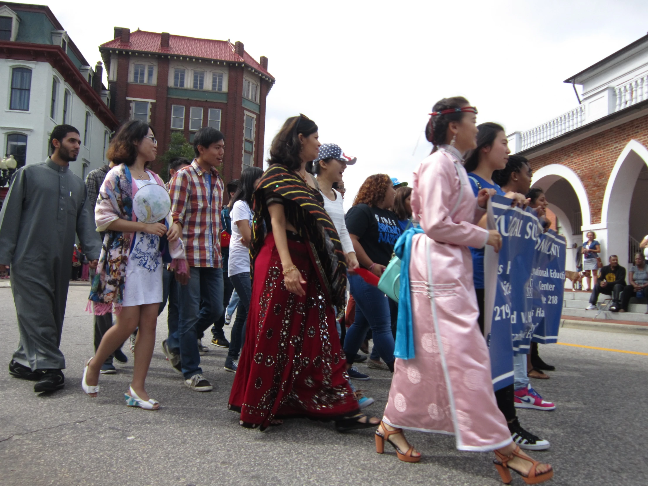 a crowd of people walking across a street holding signs