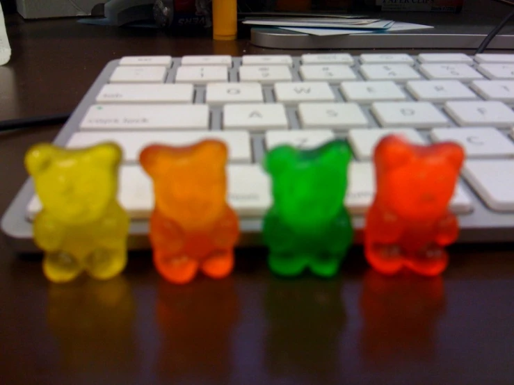 three small gummy bears placed around a computer keyboard