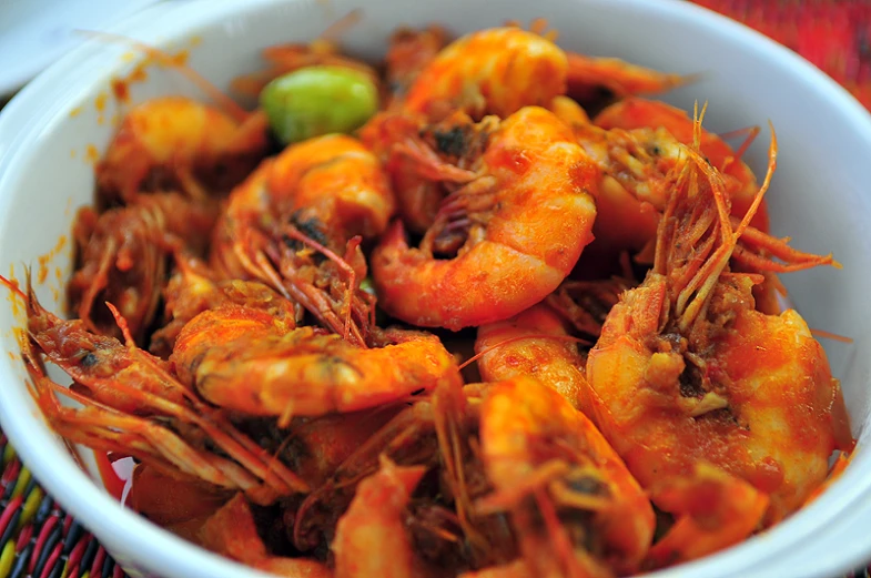 a white bowl filled with lots of cooked shrimp