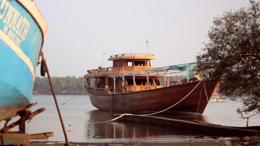 an old boat docked in a river next to a tree