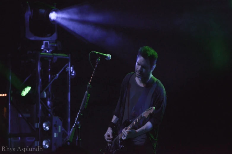 a man playing guitar while standing next to a microphone