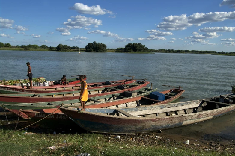 two boats that are on the beach with people near them