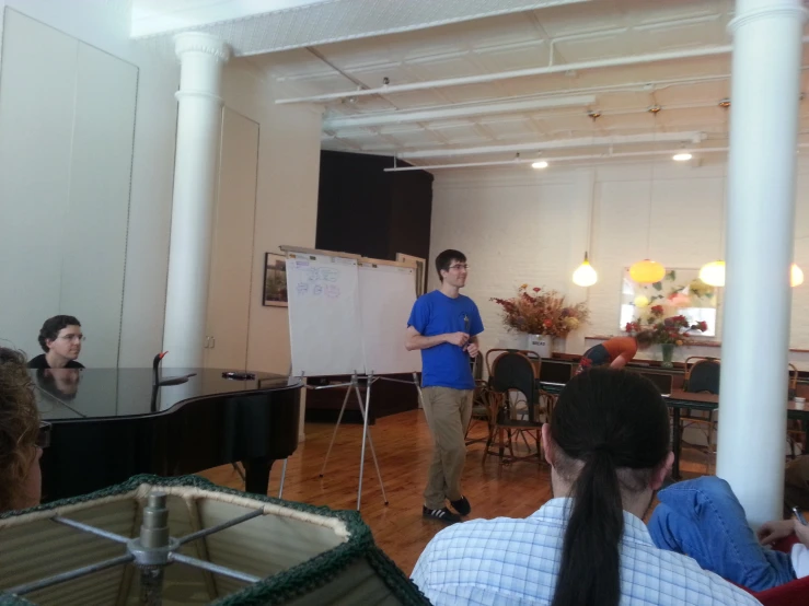 a man in a blue shirt stands by a white board