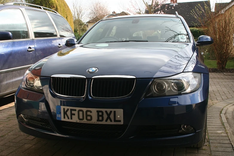 there is a blue bmw car parked beside a brown car