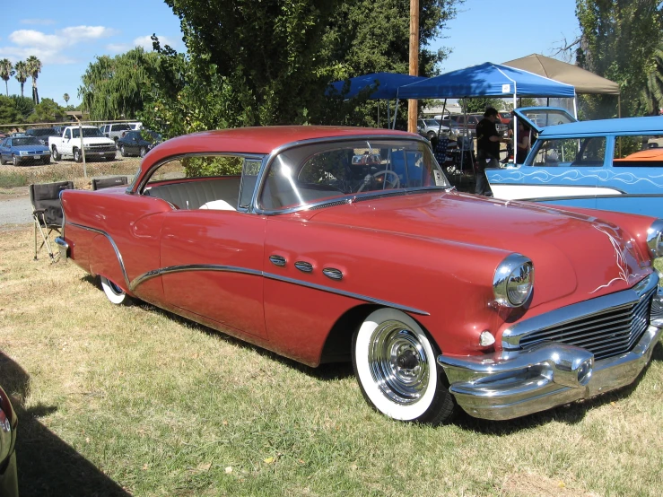 two old fashioned cars parked in front of a blue car