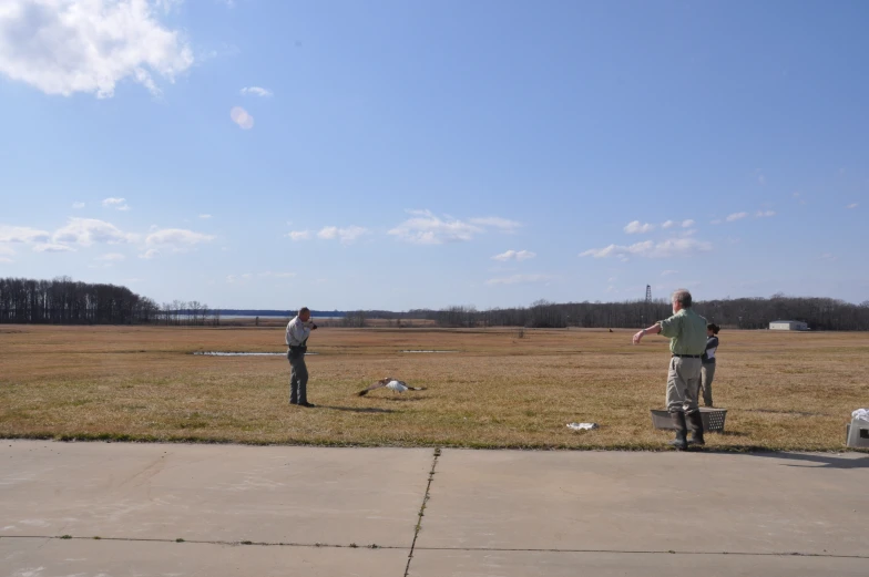 two men are standing and playing frisbee in a field