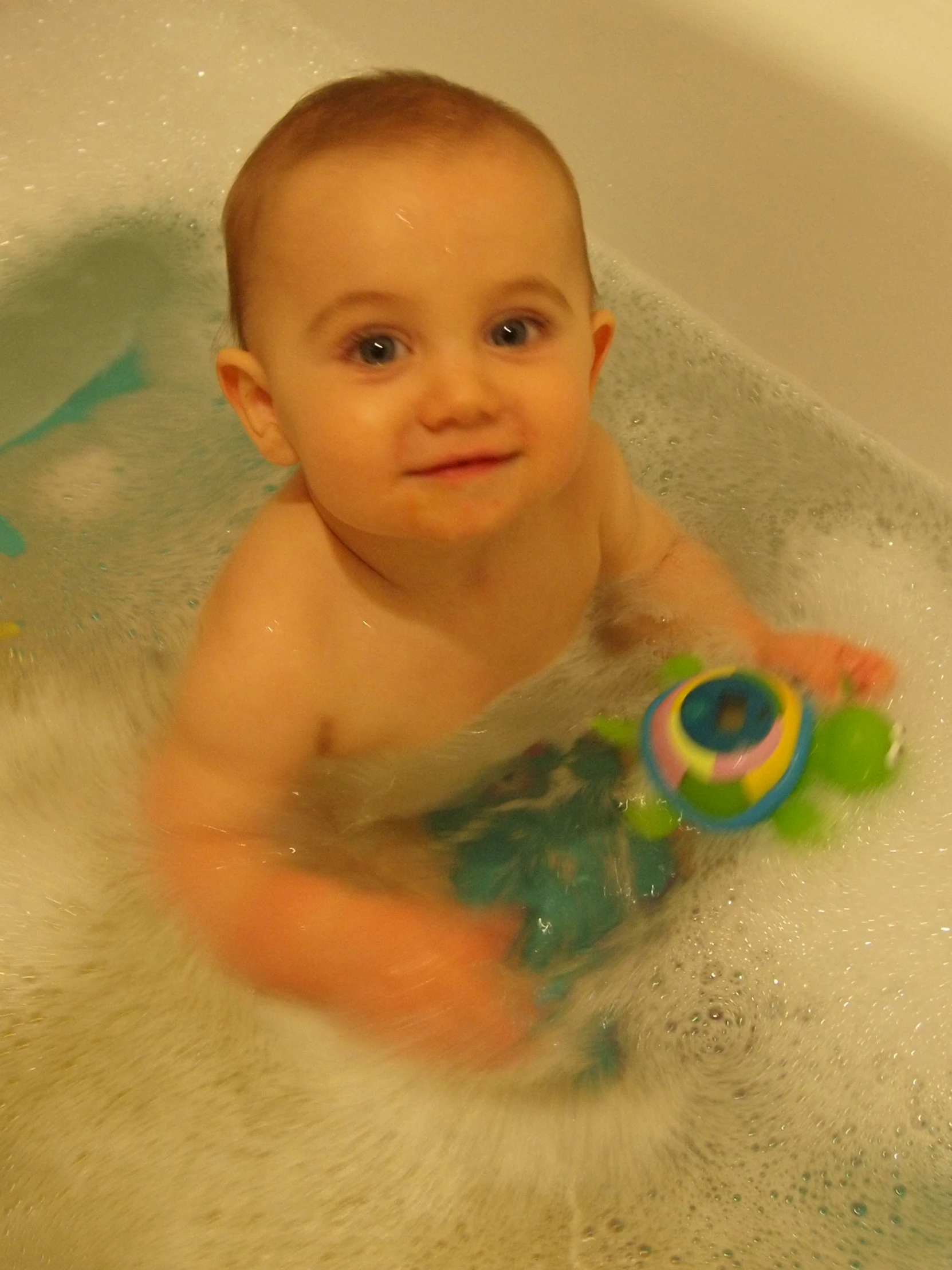 a little baby boy is in the bathtub and playing with a toy