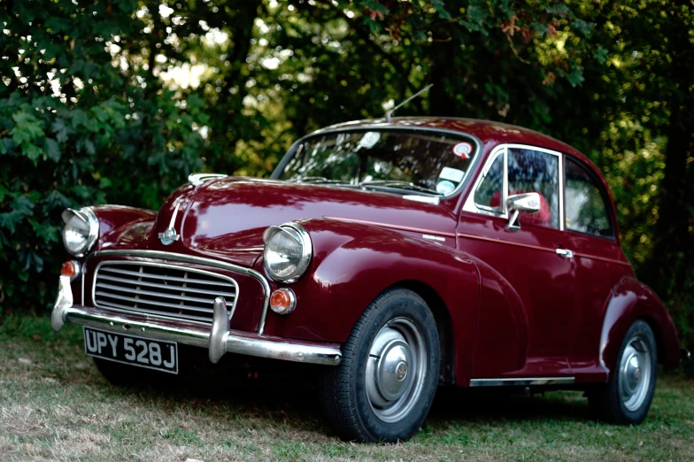 a vintage maroon car sitting in a field