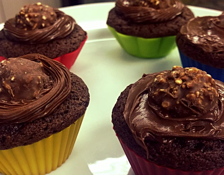 close up view of four cupcakes with chocolate frosting
