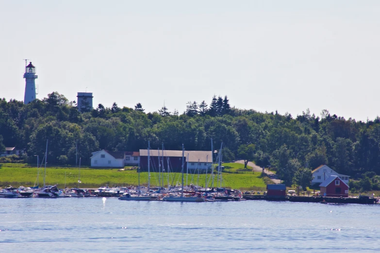 a small lighthouse on a lush green hillside over looking the water