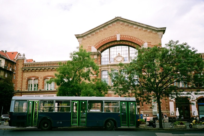 a passenger bus parked outside a building near a tree