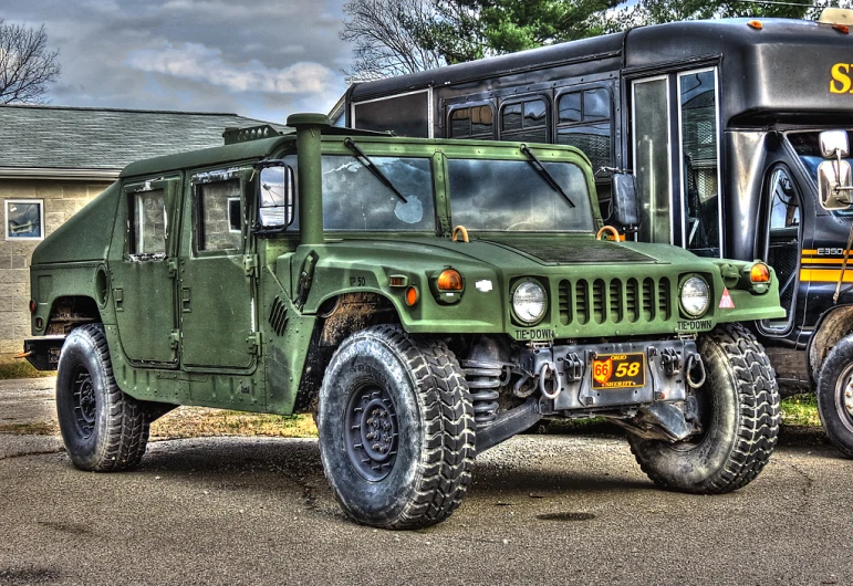 a green military truck and a black bus on pavement