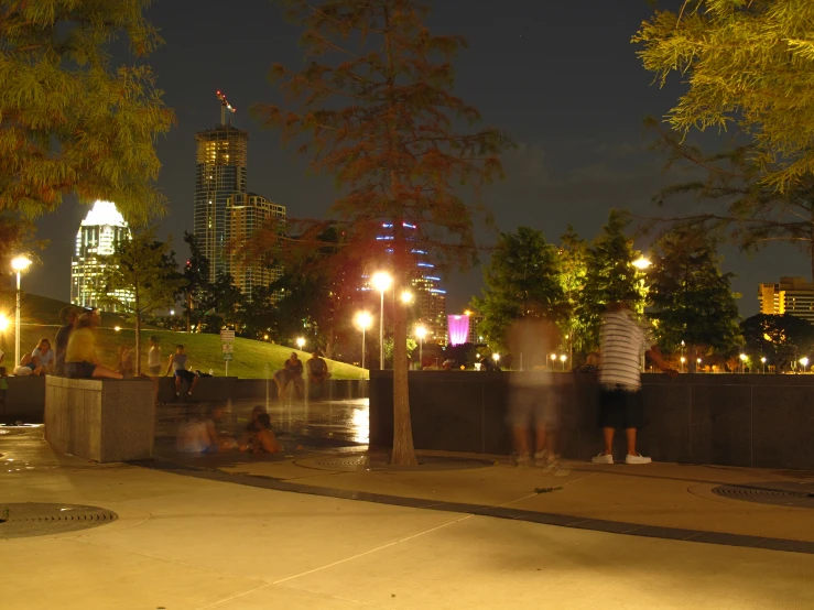 two men are walking down the sidewalk near a fountain