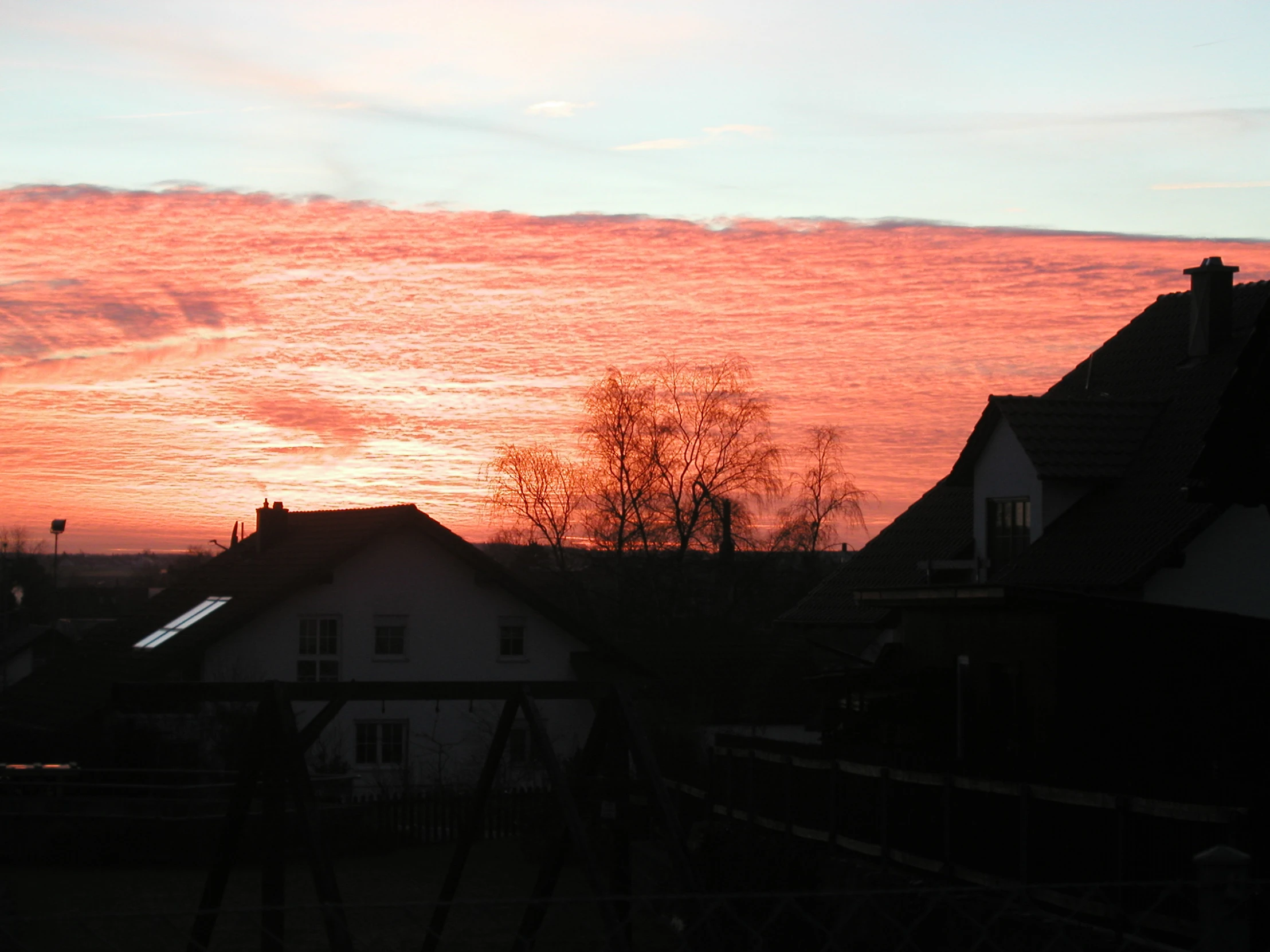 a red and blue sky with the sun setting