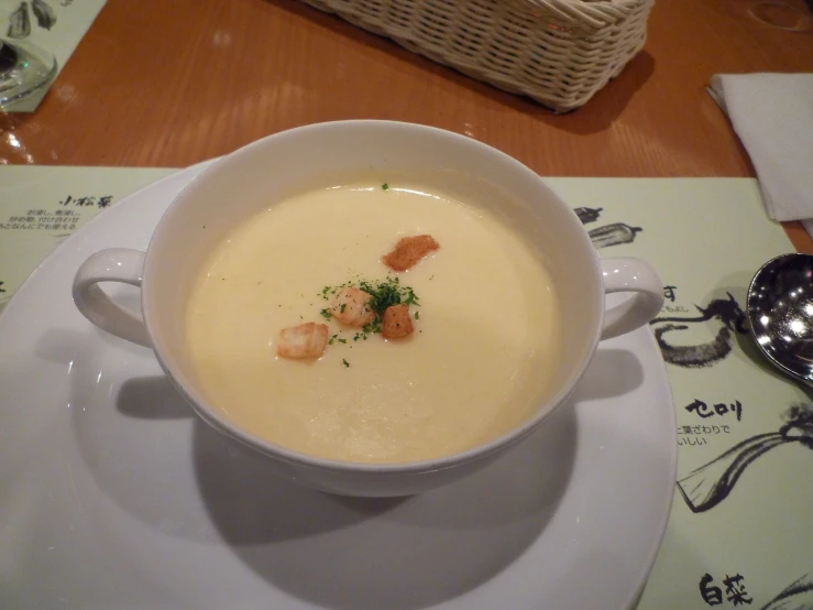 a bowl of soup with a garnish and a spoon on the plate