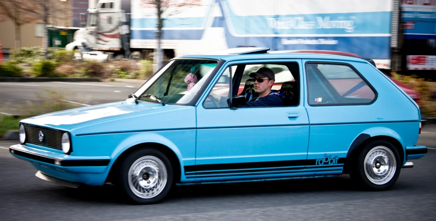 a man driving in his bright blue compact vehicle