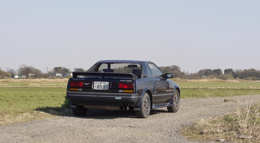 a black hatchback car sitting on top of a gravel road