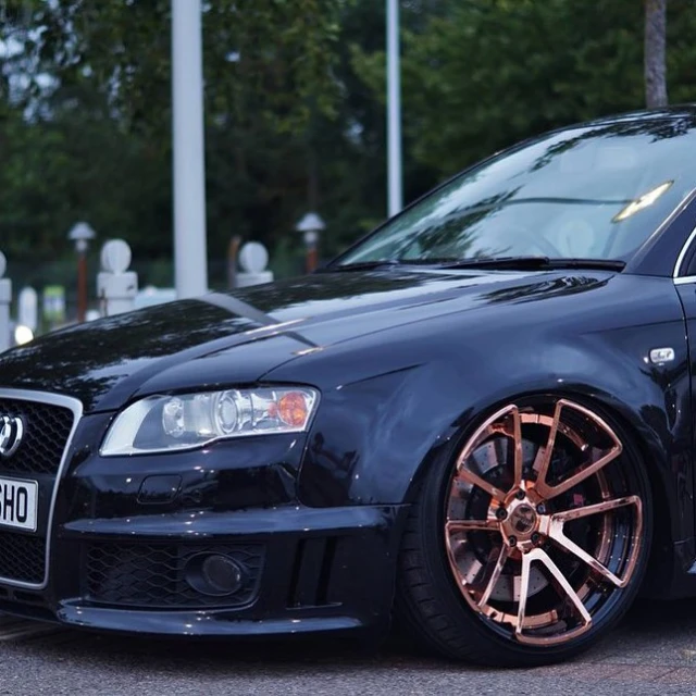 a black car with gold rims parked on a street