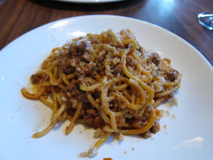 a white plate full of spaghetti with meat toppings