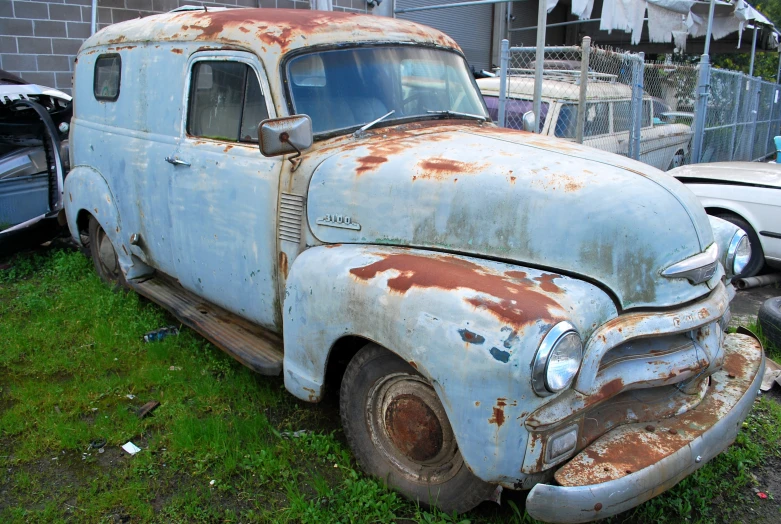 an old rusted out car and other older cars in the yard