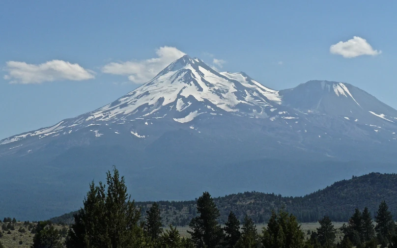 a very tall snow covered mountain covered in trees