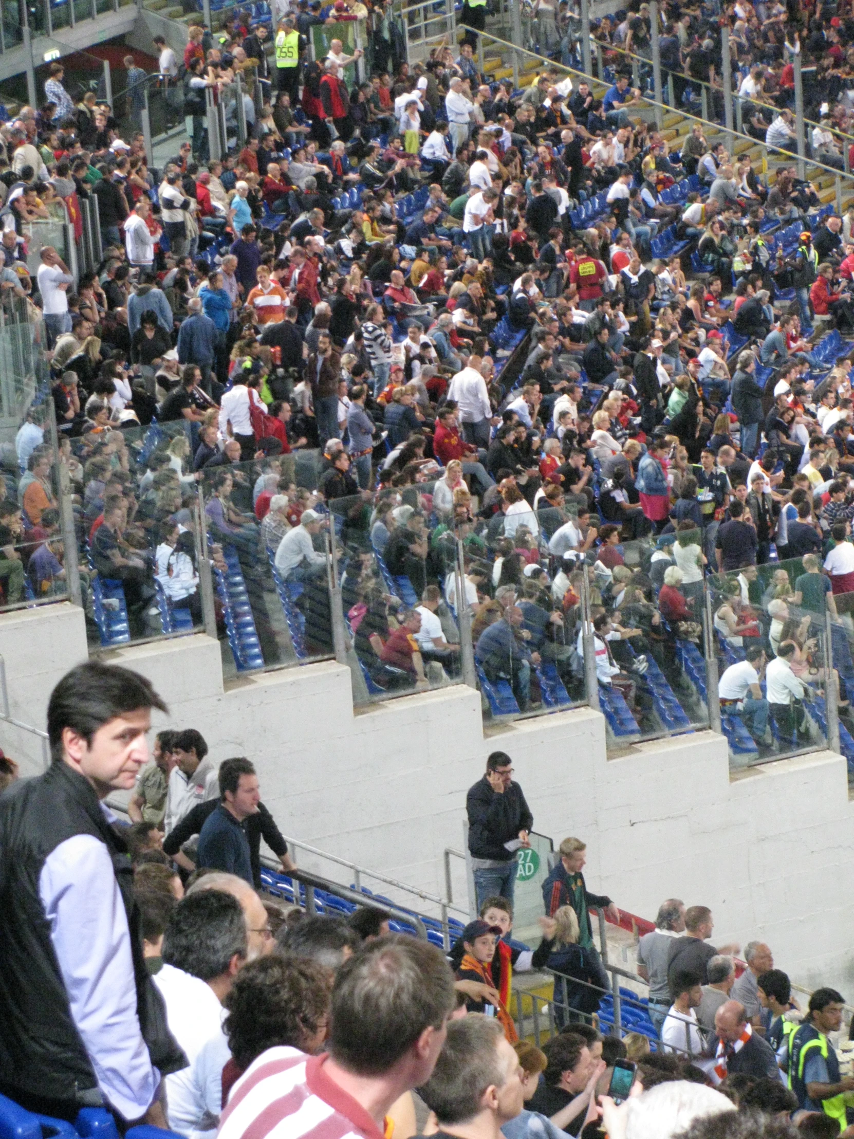 two men in the stands as one man sits on a bench