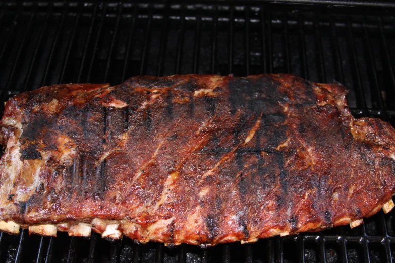 a large portion of meat is cooking on an open grill