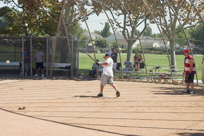 a man in white shirt standing next to a baseball bat