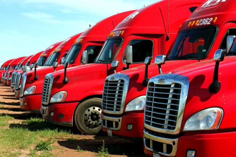 a row of red semi trucks parked next to each other