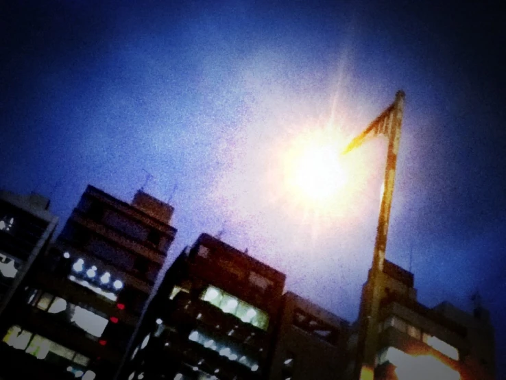 a tall light post surrounded by buildings on a cloudy day