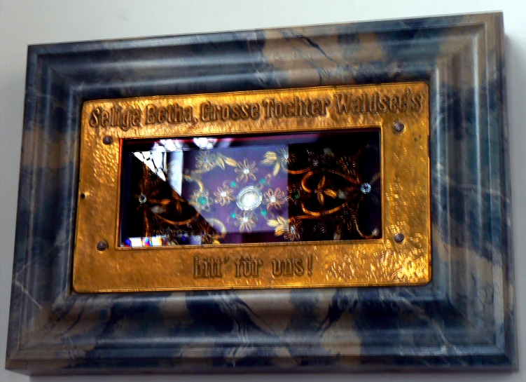 an ornate ss and marble clock frame in a dark wood frame