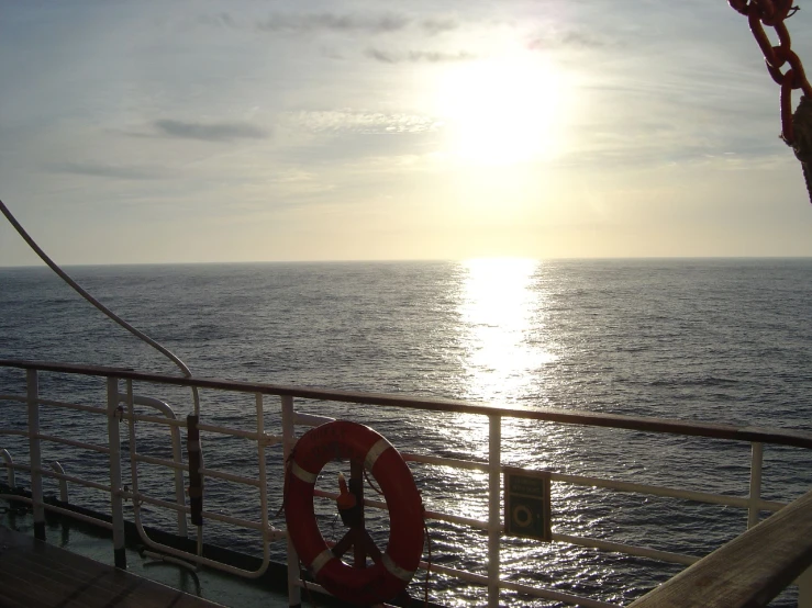 a boat on the ocean has the sun setting behind it