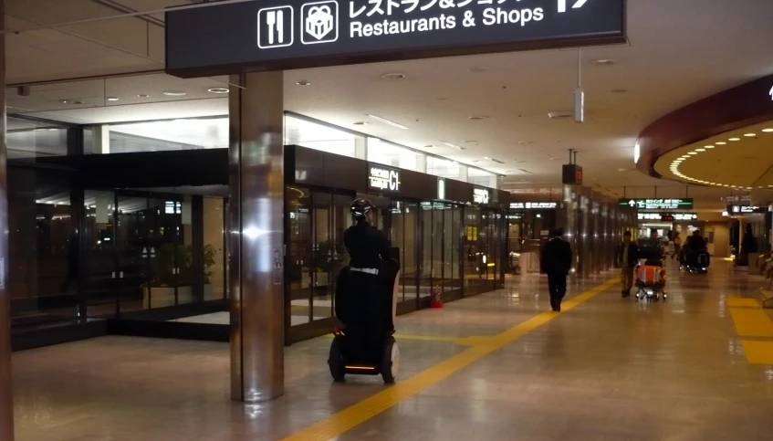 a luggage cart driving down a lobby filled with people