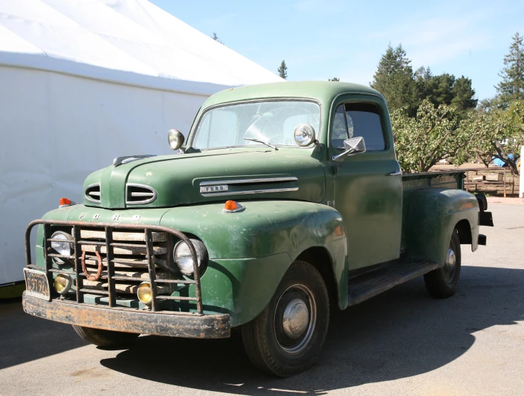 the old green pick up truck is parked in the lot