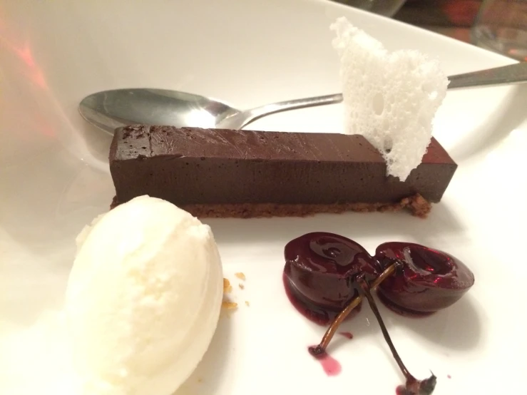 dessert on plate next to spoon and utensils on table