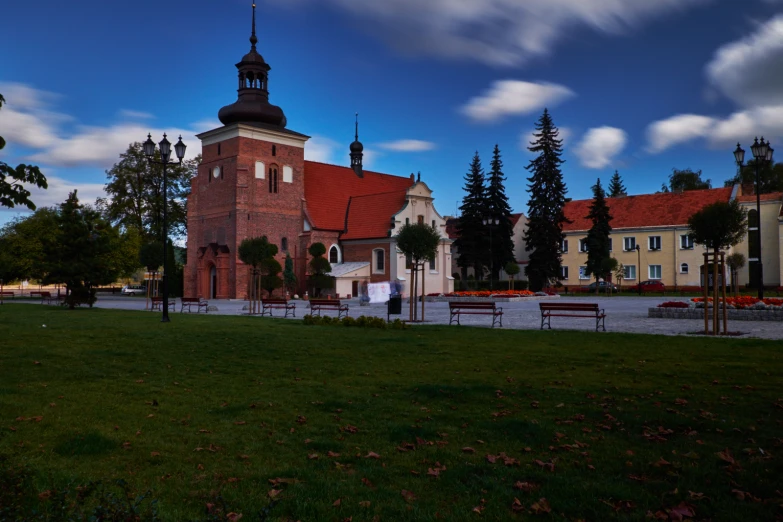 a brick church surrounded by trees and a green field