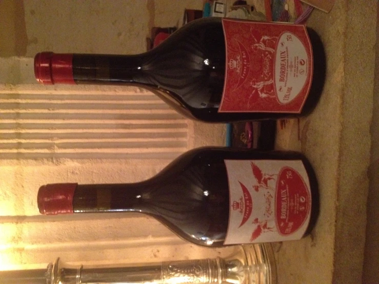 two bottles sitting on a counter beside a window