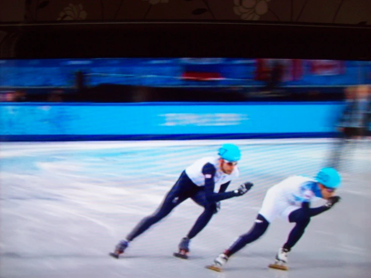 a couple of men skate down a street on ice
