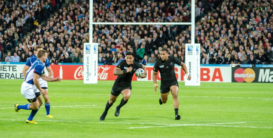 men are running on a field while one player carries a soccer ball