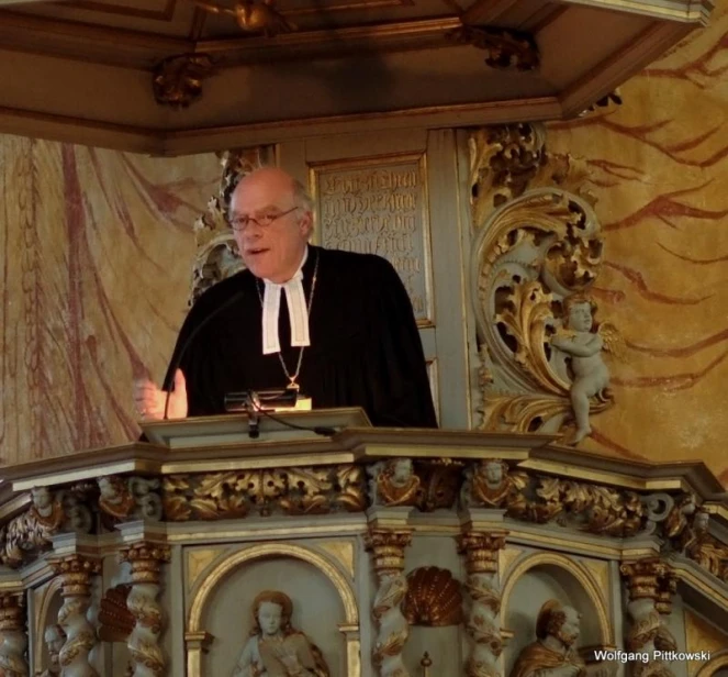 a priest with a black robe stands at the top of a podium