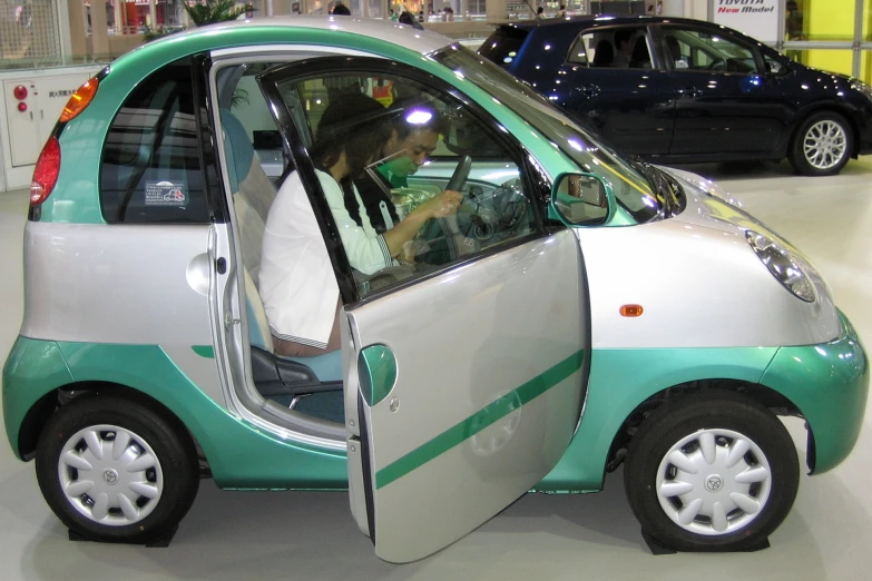 this small green and white car is in a showroom