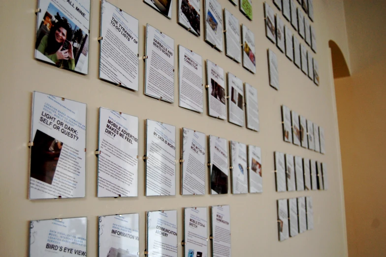 several bulletins are arranged on a wall in front of a tan colored wall