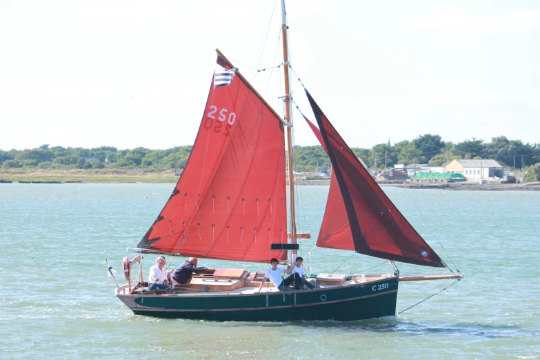 a small sailboat with red sails in the water