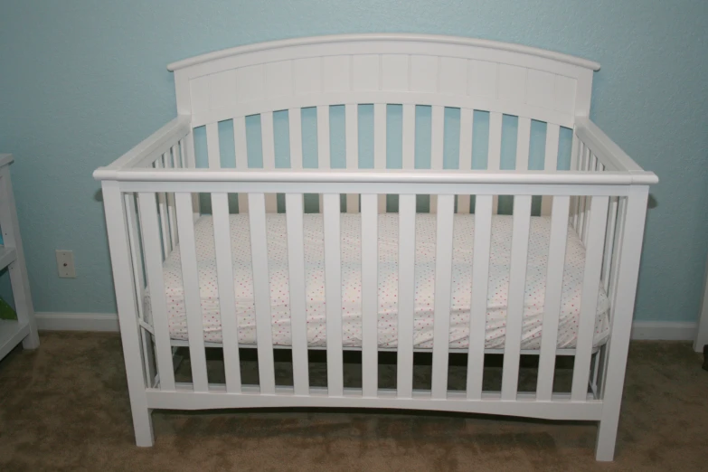 a white crib sits in the corner of the room