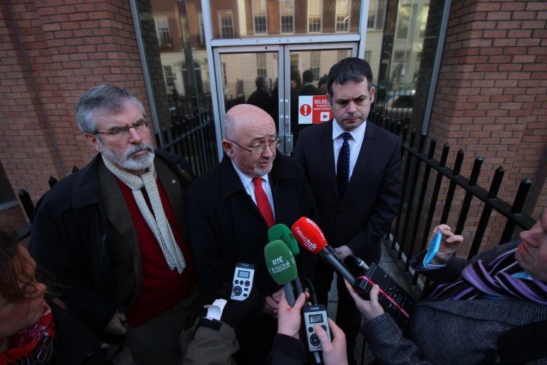 the three men are talking to the reporters