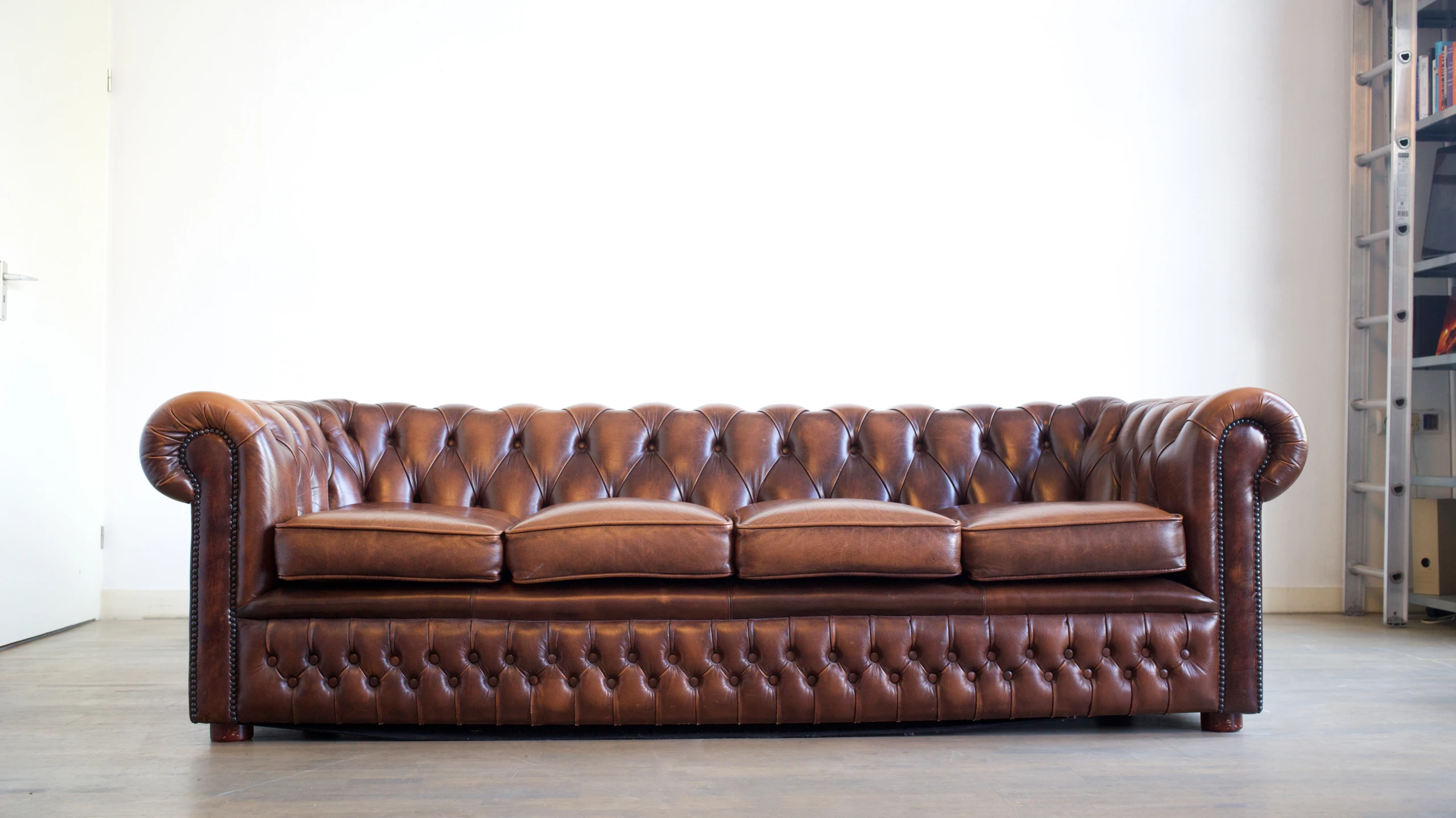 an old sofa with leather arms and ons, sits in the corner of a room